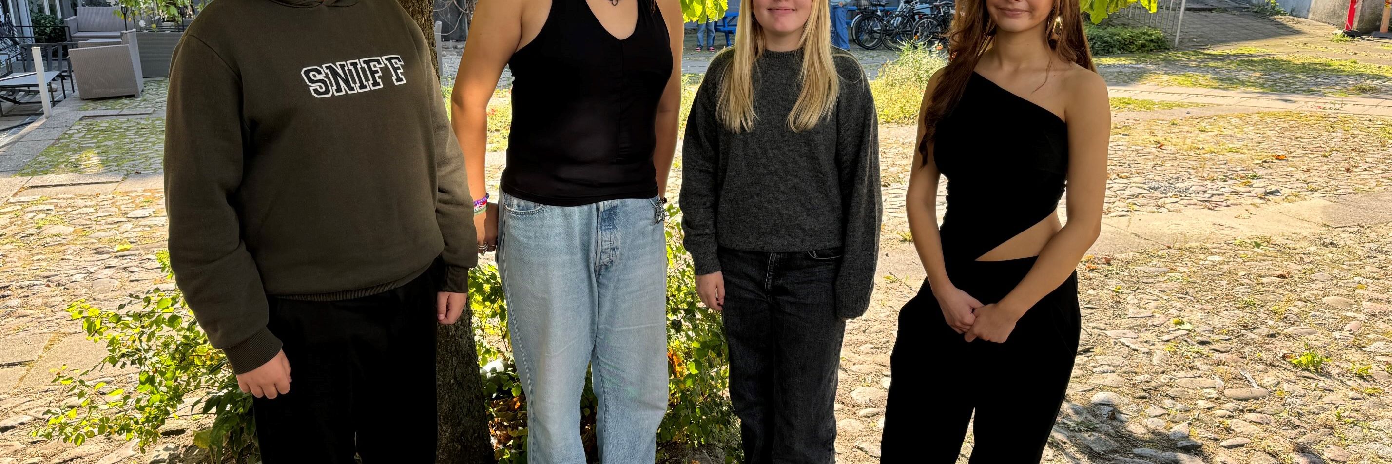 4 unge mennesker der står foran et tre